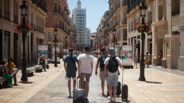 turisti straini cu bagaje merg pe strada in malaga spania