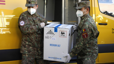 Doi militari descarcă din mașină cutii u vaccinuri.