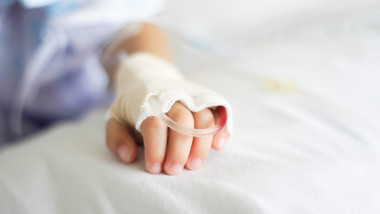 mana unui copil cu branula pe patul de spital