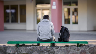 adolescent care sta cu spatele, pe o bancă