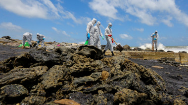 angajati ai armatei îmbracati in echipament de protectie adună reziduuri din plastic si deseuri chimice de pe plaja din sri lanka