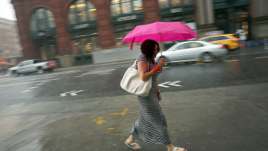 o femeie merge cu umbrela prin ploaia torentiala