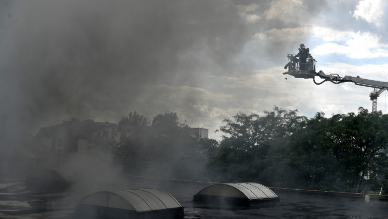 pompier pe un acoperis inconjurat de mult fum