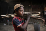 Copil din Bangladesh care cară pe umeri bețe din fier