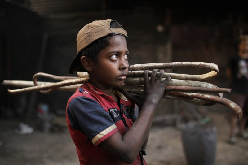 Copil din Bangladesh care cară pe umeri bețe din fier
