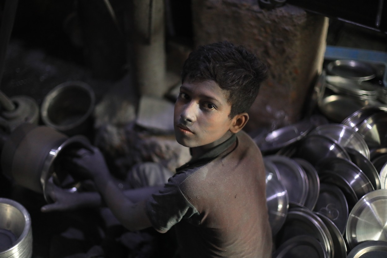Copil de 13 ani din Bangladesh care lucrează la o fabrică de aluminiu.