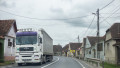 camion pe sosea care trece printre case
