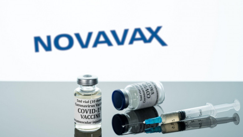 două doze de vaccin anti-covid, o seringă, și numele companiei Novavax pe fundal