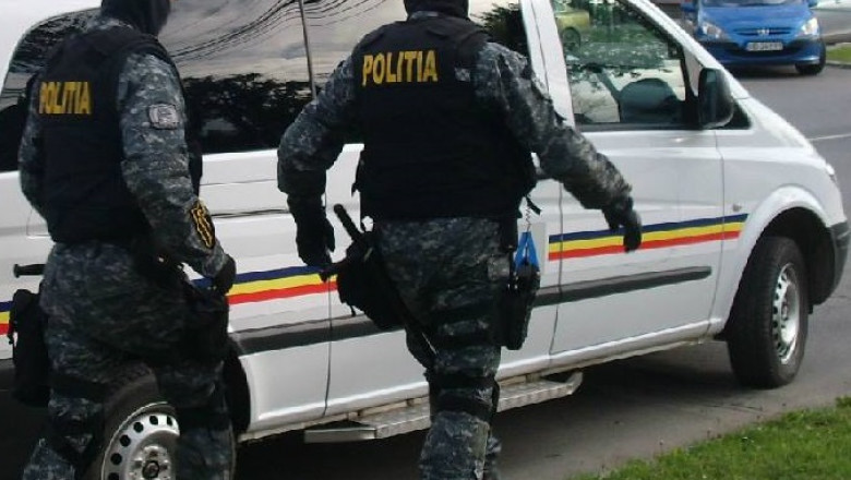 politisti cu uniforme de protectie langa o masina de politie