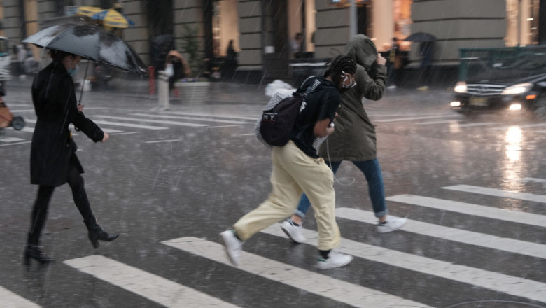 oameni alearga prin ploaie pe o trecere de pietoni