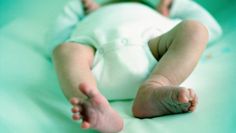 Un bebelus stă culcat pe spate si i se vad în prim-plan piciorusele