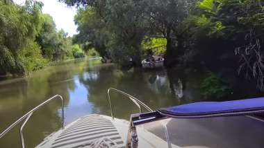 O barcă înaintează pe un canal din Delta Dunării.