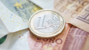 O monedă de un euro este așezată pe mai multe bacnote de euro
