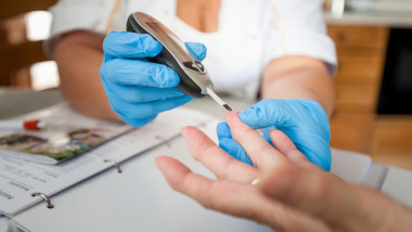O asistenta face test glicemie din deget unui pacient cu diabet