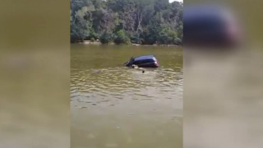 masina cazuta in apa si oameni care inoata spre ea