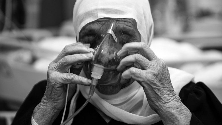 fotografie alb negru cu o femeie batrana care respiră cu ajutorul unui tub de oxigen
