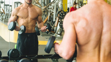 Un tânăr face exerciții de forță la sala de sport.