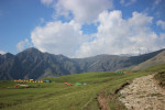 A Trekking Campsite in a meadow in himalaya during Roopkund Trek alongwith mountains in background.