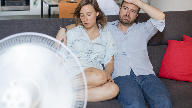 un cuplu de tineri moare de cald in casa in fata unui ventilator
