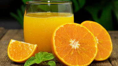 pahar de suc de portocale langa portocala taiata
