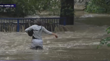 femeie mergand pe o strada inundată, in apă pana la brâu