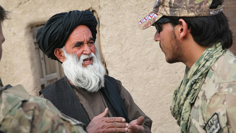 bărbat în vârstă cu turban și barbă albă vorbește unui alt bărbat