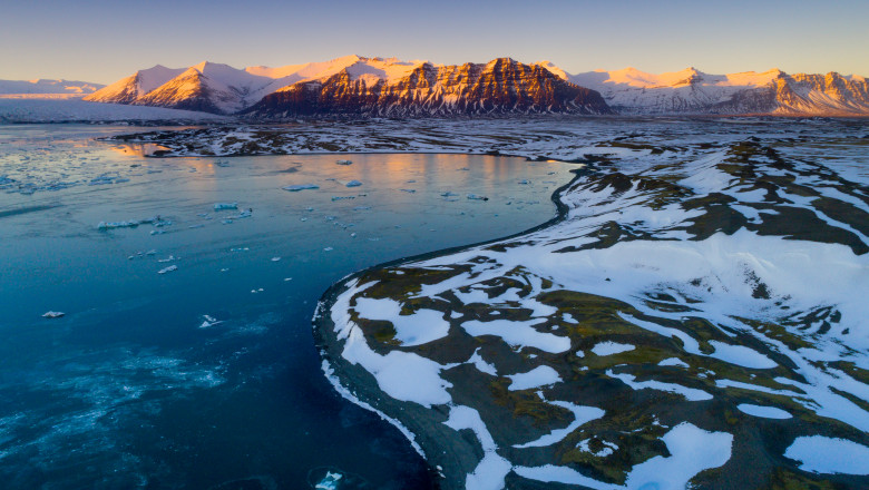 regiune polara cu zapada topita ce dezveleste roci si verdeata