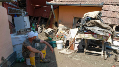 barbat care se uita la lucrurile scoase din casa in curte in urma unei inundatii