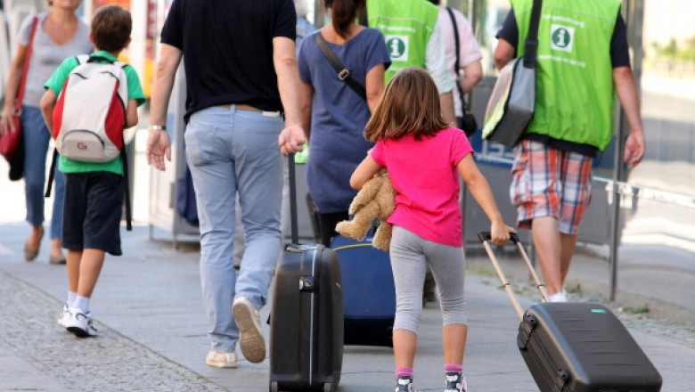 Adulți și copii cu bagaje, pe stradă.