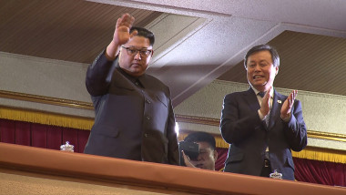 Kim Jong-un face cu mâna dintr-o lojă. În dreapta lui este un oficial nord-coreean
