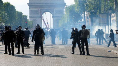 Jandarmi și protestatari într-un nor de gaz cu Arcul de Triumf francez pe fundal