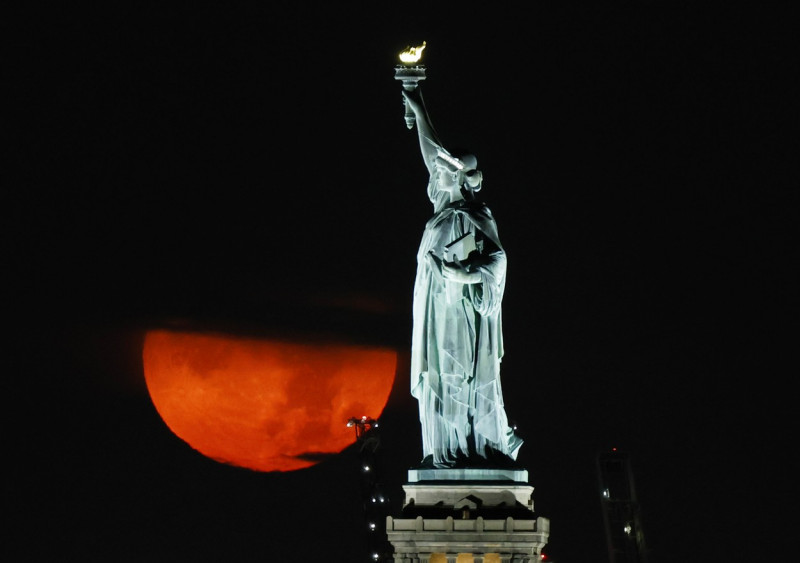 Full Buck Moon Sets Behind the Statue of Liberty in New York