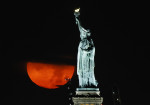 Full Buck Moon Sets Behind the Statue of Liberty in New York