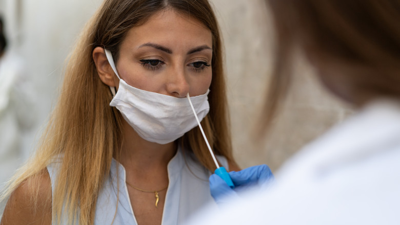 femeie careia i se recolteaza o proba din nas pentru testare anti-covid