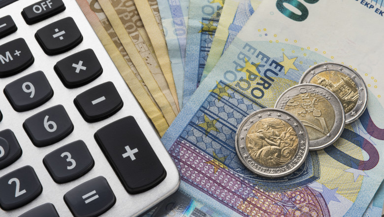 bancnote si monede euro langa un calculator