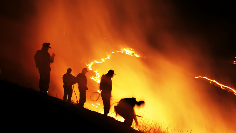 Oameni care privesc un incendiu de vegetație