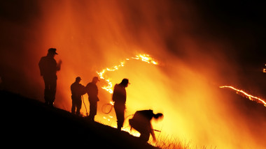 Oameni care privesc un incendiu de vegetație