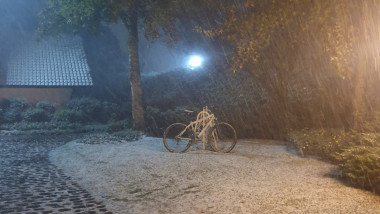 bicicleta sprijinita de stalp in ninsoare puternica