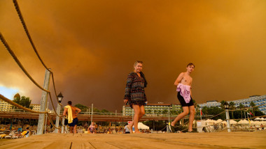 turisti avand in spate cerul rosu de la incendii si fum