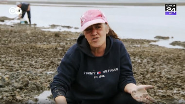 femie care explica ceva in timp ce scormoneste prin noroi pe malul unei ape