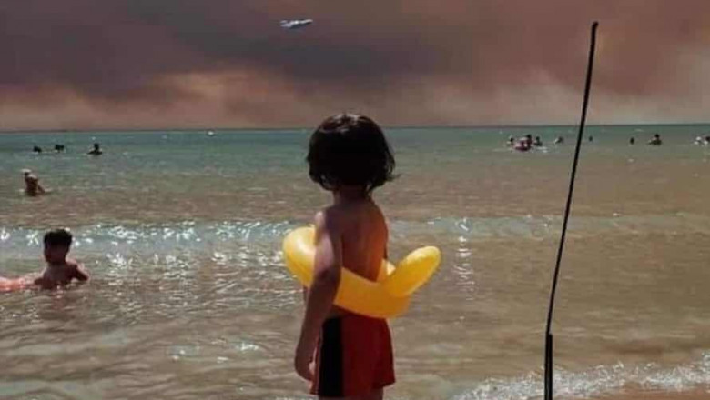 Un copil aflat pe o plajă se uită la fumul provocat de incendiile din Turcia