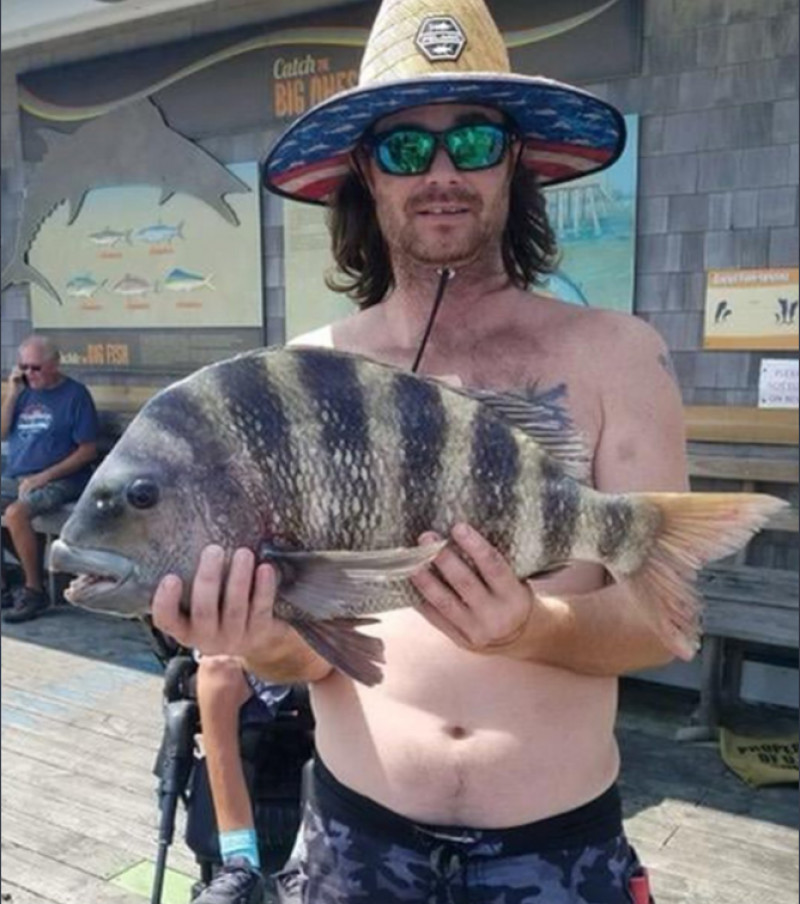 Un bărbat cu pălărie ține în mâini peștele-cap-de-aoie