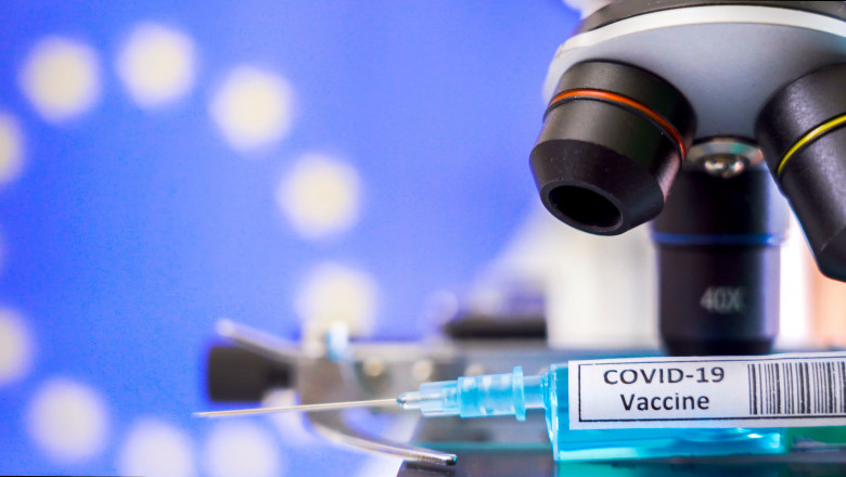 The objective lens of the microscope and the syringe for Covid-19 vaccine for coronavirus