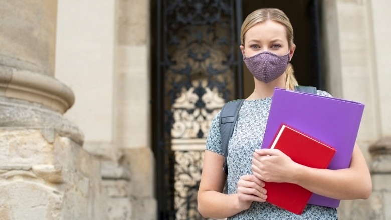 Portrait Of Female Student Standing Outside College Or University Building Wearing Face Mask During Covid-19 Pandemic