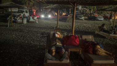 Grecii care și-au pierdut casele și au fost evacuați din calea flăcărilor dorm pe o plajă
