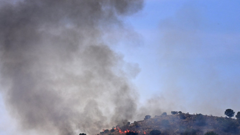 fum care se ridica de la un incendiu de vegetatie intr-o zona de deal