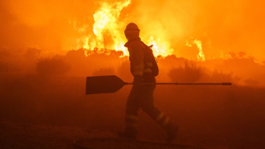 profilul unui pompier cu lopata noaptea pe fundalul unor incendii de vegetatie