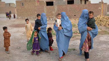 Femei dintr-o familie afgană strămutată din cauza conflictului dintre talibani și forțele de securitate ale guvernului care poartă burqa.