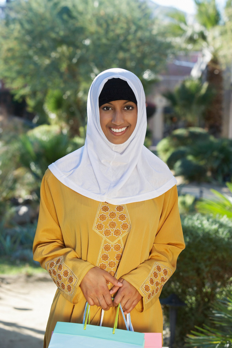 Portrait of young muslim woman with shopping bag, smiling