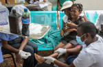 Un medic îngrijește piciorul unei fete rănite în cutremurul puternic din Haiti din august 2021